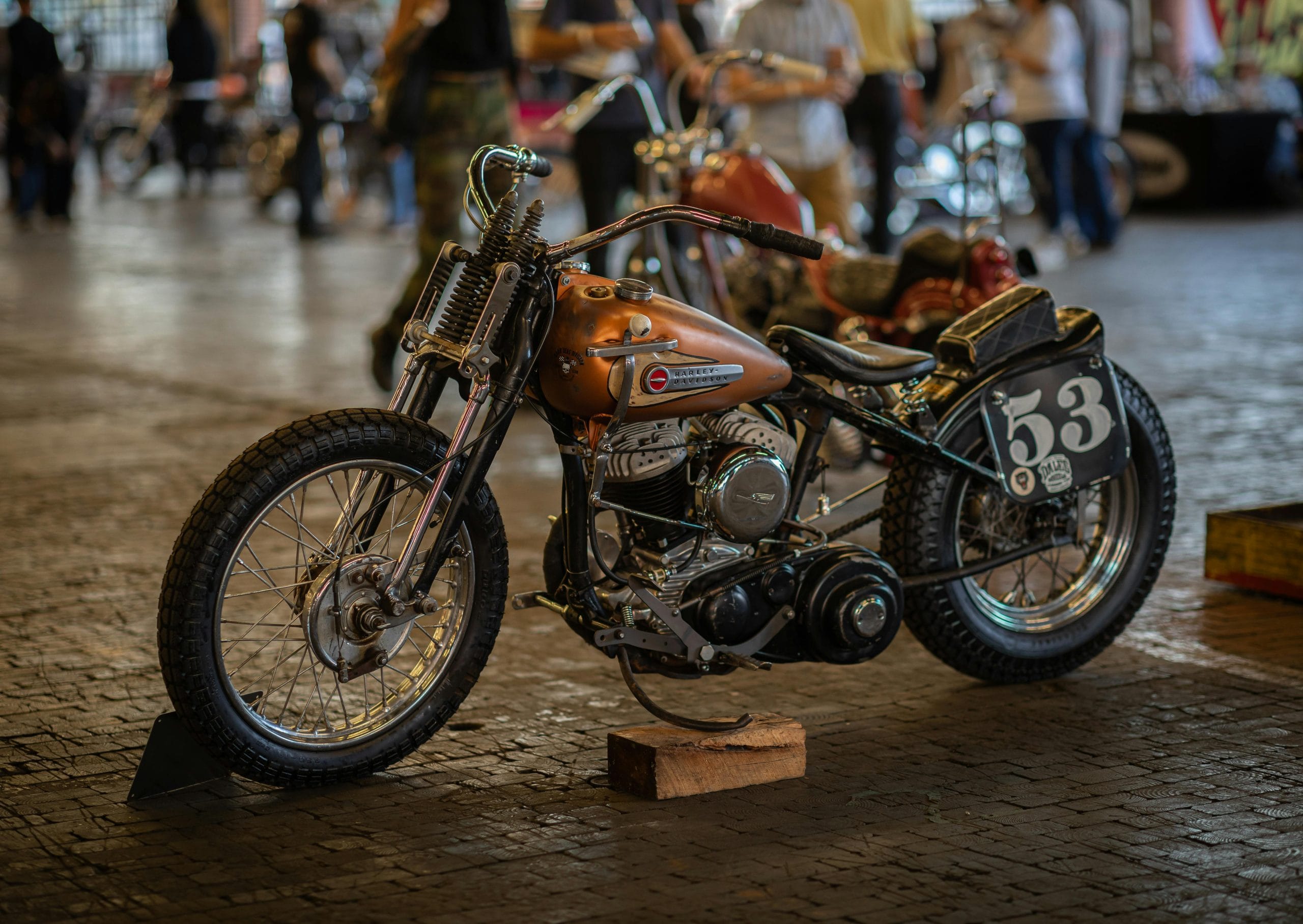 A classic vintage motorcycle parked indoors during an exhibition, showcasing retro style and intricate mechanics.